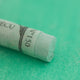 A close-up of a green Sennelier extra soft pastel. on the same coloured background, with the colour information printed on the paper wrap.