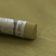 A close-up of a green Sennelier extra soft pastel, on the same coloured background, with the colour information printed on the paper wrap.