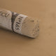 A close-up of a brown Sennelier extra soft pastel. on the same coloured background, with the colour information printed on the paper wrap.