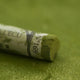 A close-up of a green Sennelier extra soft pastel. on the same coloured background, with the colour information printed on the paper wrap.