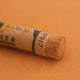 A close-up of a Sennelier extra soft pastel on a brown background with the colour information printed on the paper wrap.