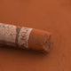 A close-up of a brown Sennelier extra soft pastel with the colour information printed on the paper wrap.
