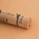 A close-up of a Sennelier extra soft pastel on a brown background with the colour information printed on the paper wrap.