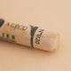 A close-up of a Sennelier extra soft pastel on a white background with the colour information printed on the paper wrap.