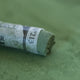 A close-up of a grey-green Sennelier extra soft pastel. on the same coloured background, with the colour information printed on the paper wrap.