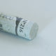 A close-up of a white Sennelier extra soft pastel. on the same coloured background, with the colour information printed on the paper wrap.