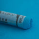 A close-up of a blue Sennelier extra soft pastel on the same coloured background, with the colour information printed on the paper wrap.