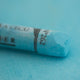 A close-up of a blue Sennelier extra soft pastel on the same coloured background, with the colour information printed on the paper wrap.