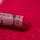 A close-up of a bright pink Sennelier extra soft pastel. on the same coloured background, with the colour information printed on the paper wrap.