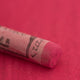 A close-up of a pink Sennelier extra soft pastel. on the same coloured background, with the colour information printed on the paper wrap.