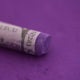  A close-up of a purple Sennelier extra soft pastel on the same coloured background, with the colour information printed on the paper wrap.