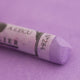  A close-up of a light purple Sennelier extra soft pastel on the same coloured background, with the colour information printed on the paper wrap.