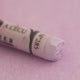  A close-up of a light purple Sennelier extra soft pastel on the same coloured background, with the colour information printed on the paper wrap.