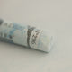 A close-up of a white Sennelier extra soft pastel on the same coloured background, with the colour information printed on the paper wrap.