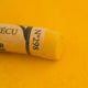 A close-up of a yellow Sennelier extra soft pastel. on the same coloured background, with the colour information printed on the paper wrap.