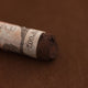 A close-up of a brown Sennelier extra soft pastel with the colour information printed on the paper wrap.