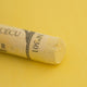 A close-up of a light yellow Sennelier extra soft pastel. on the same coloured background, with the colour information printed on the paper wrap.