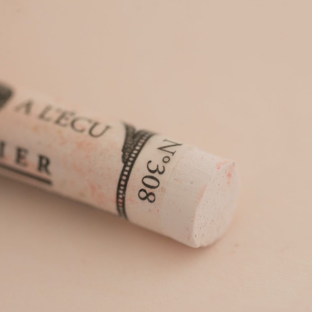 A close-up of a white Sennelier extra soft pastel on the same coloured background, with the colour information printed on the paper wrap.