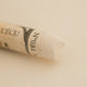 A close-up of a white Sennelier extra soft pastel with the colour information printed on the paper wrap.
