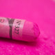 A close-up of a vibrant purple Sennelier extra soft pastel. on the same coloured background, with the colour information printed on the paper wrap.