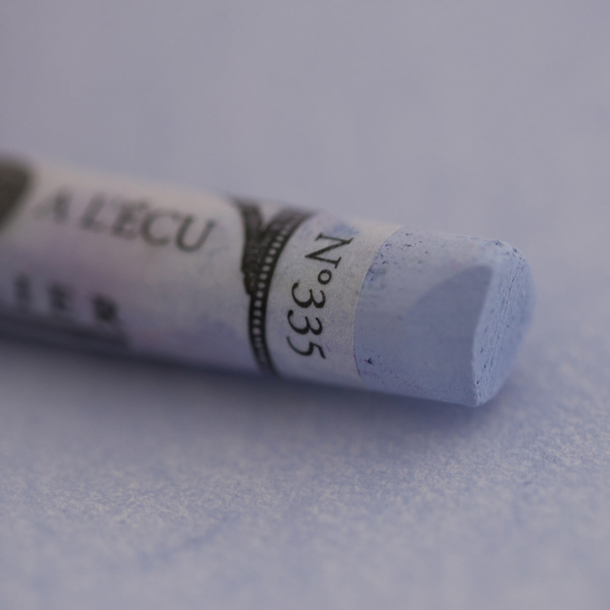  A close-up of a blue Sennelier extra soft pastel on the same coloured background, with the colour information printed on the paper wrap.
