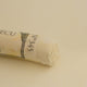 A close-up of a pale yellow Sennelier extra soft pastel. on the same coloured background, with the colour information printed on the paper wrap.