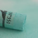 A close-up of a green Sennelier extra soft pastel. on the same coloured background, with the colour information printed on the paper wrap.