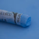 A close-up of a blue Sennelier extra soft pastel on the same coloured background, with the colour information printed on the paper wrap.