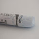 A close-up of a white Sennelier extra soft pastel on the same coloured background, with the colour information printed on the paper wrap.