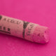 A close-up of a red Sennelier extra soft pastel. on the same coloured background, with the colour information printed on the paper wrap.