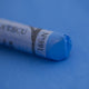 A close-up of a blue Sennelier extra soft pastel on the same coloured background, with the colour information printed on the paper wrap.