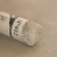 A close-up of a light brown Sennelier extra soft pastel. on the same coloured background, with the colour information printed on the paper wrap.