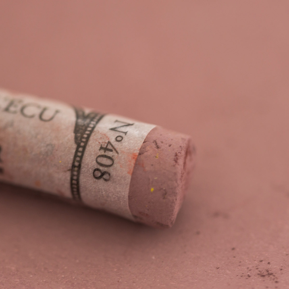 A close-up of a brown Sennelier extra soft pastel with the colour information printed on the paper wrap.