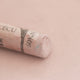 A close-up of a light brown Sennelier extra soft pastel with the colour information printed on the paper wrap.