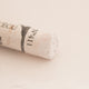 A close-up of a white Sennelier extra soft pastel with the colour information printed on the paper wrap.