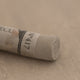 A close-up of a brown Sennelier extra soft pastel with the colour information printed on the paper wrap.