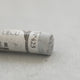 A close-up of a light grey Sennelier extra soft pastel. on the same coloured background, with the colour information printed on the paper wrap.
