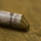 A close-up of a brown Sennelier extra soft pastel. on the same coloured background, with the colour information printed on the paper wrap.