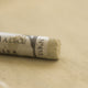 A close-up of a light brown Sennelier extra soft pastel. on the same coloured background, with the colour information printed on the paper wrap.