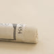A close-up of a white Sennelier extra soft pastel. on the same coloured background, with the colour information printed on the paper wrap.