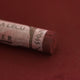 A close-up of a brown Sennelier extra soft pastel with the colour information printed on the paper wrap.
