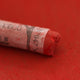 A close-up of a red Sennelier extra soft pastel with the colour information printed on the paper wrap.