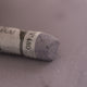 A close-up of a grey Sennelier extra soft pastel. on the same coloured background, with the colour information printed on the paper wrap.