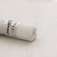 A close-up of a white Sennelier extra soft pastel. on the same coloured background, with the colour information printed on the paper wrap.