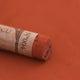 A close-up of a brown Sennelier extra soft pastel with the colour information printed on the paper wrap.