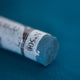 A close-up of deep blue Sennelier extra soft pastel. on the same coloured background, with the colour information printed on the paper wrap.