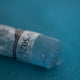 A close-up of a blue-green Sennelier extra soft pastel. on the same coloured background, with the colour information printed on the paper wrap.