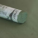 A close-up of a brown Sennelier extra soft pastel. on the same coloured background, with the colour information printed on the paper wrap.