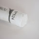 A close-up of a white Sennelier extra soft pastel. on the same coloured background, with the colour information printed on the paper wrap.