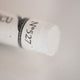 A close-up of a white Sennelier extra soft pastel. on the same coloured background, with the colour information printed on the paper wrap.